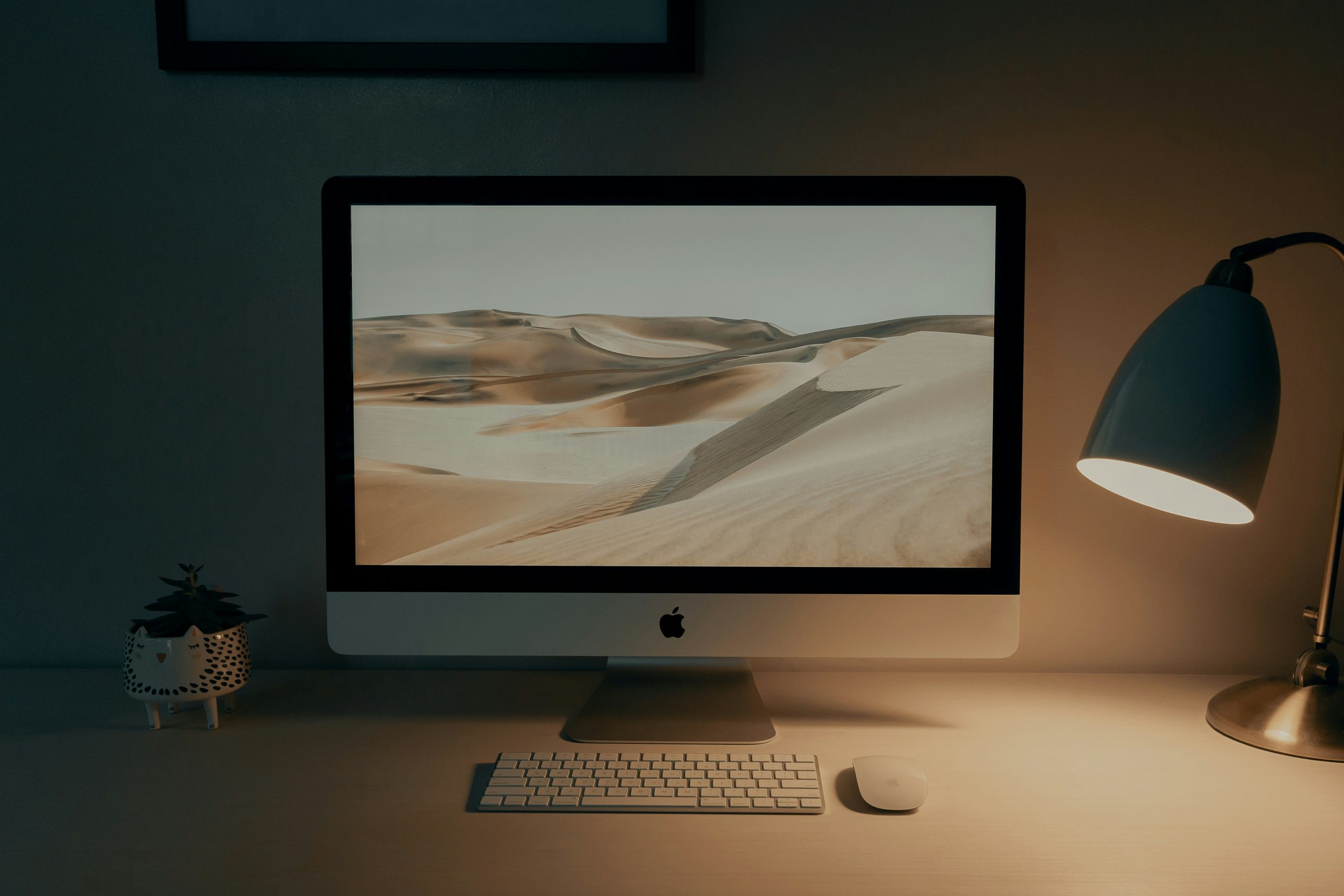 Silver iMac di atas meja kayu dengan pencahayaan natural